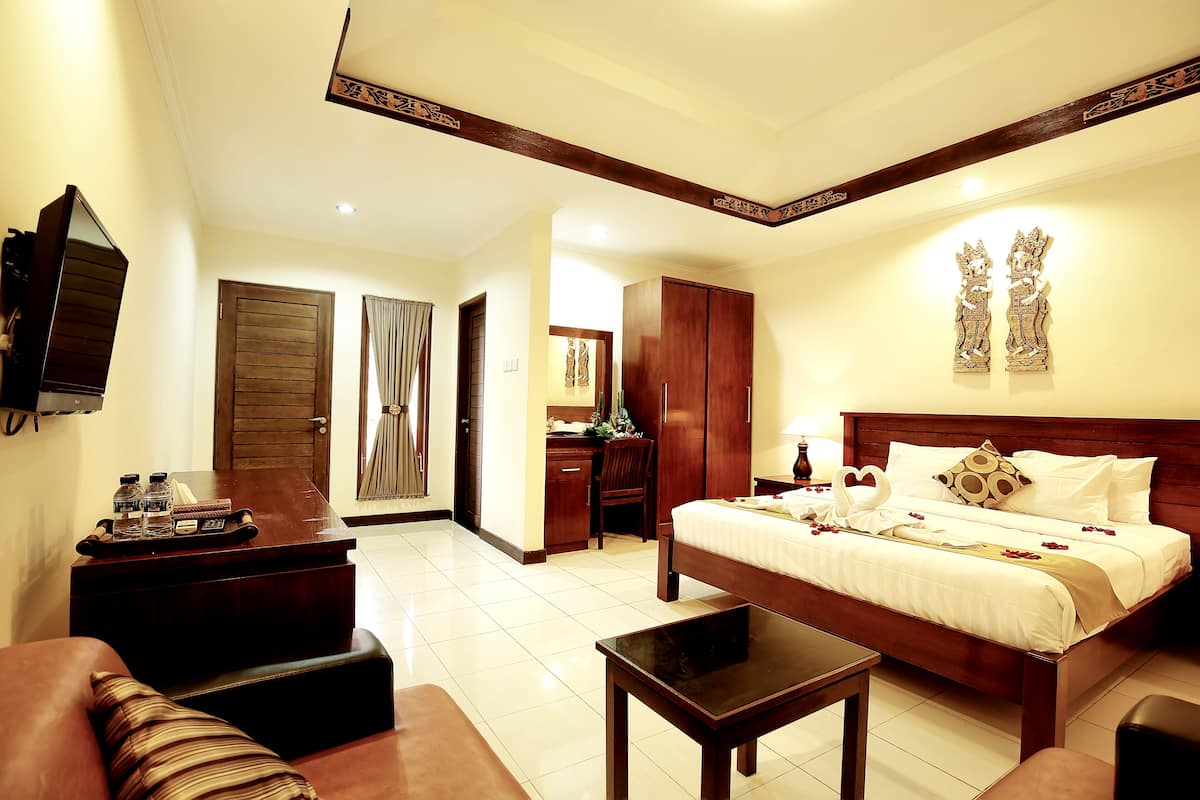 A hotel room with a bed, a desk, a chair, a sofa, and a small table.