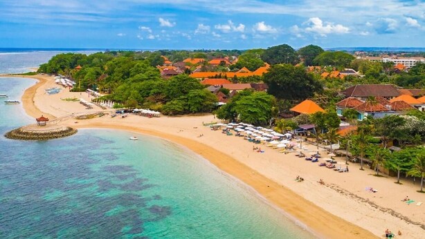 A coastal resort with a sandy beach, clear turquoise waters, and lush greenery. - Hotel Segara Agung (Denpasar)