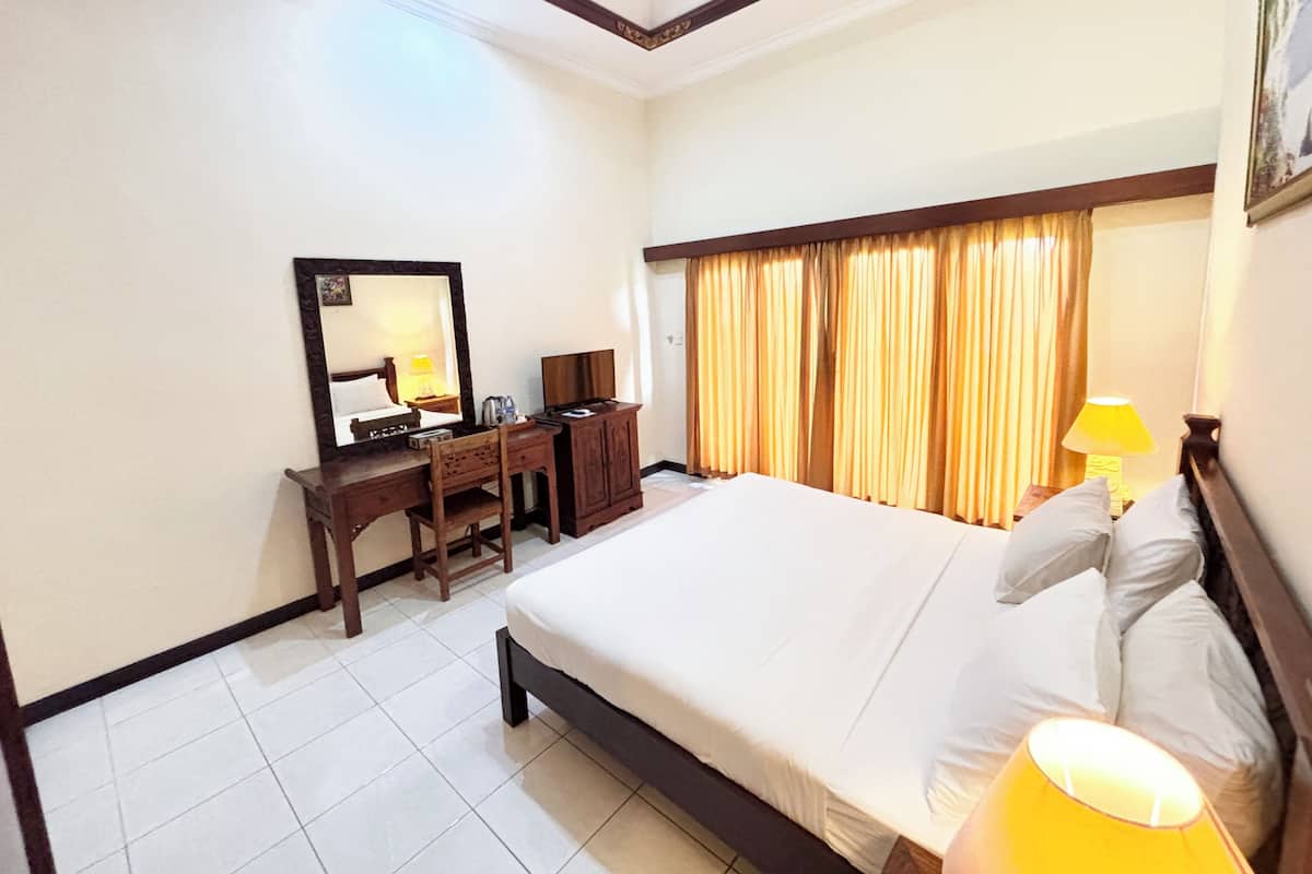 A hotel room with a bed, a desk, a chair, a mirror, a television, and curtains.