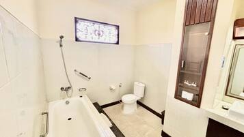 Un baño con bañera, inodoro y espejo.