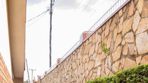 Un estrecho sendero de piedra bordeado por un muro de piedra y un seto.
