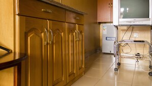 Una cocina con armarios de madera, un refrigerador y un televisor sobre un mueble.