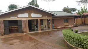 A building with a covered entrance and a small outdoor seating area. - Palace Motel (Fort Portal)