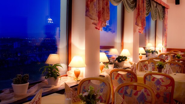 A restaurant with tables set for dining, potted plants, and lamps. - Hotel Restaurant Rheinkrone Koblenz (Koblenz)