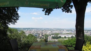 An outdoor seating area with a table and chairs, overlooking a cityscape. - Hotel Restaurant Rheinkrone Koblenz (Koblenz)