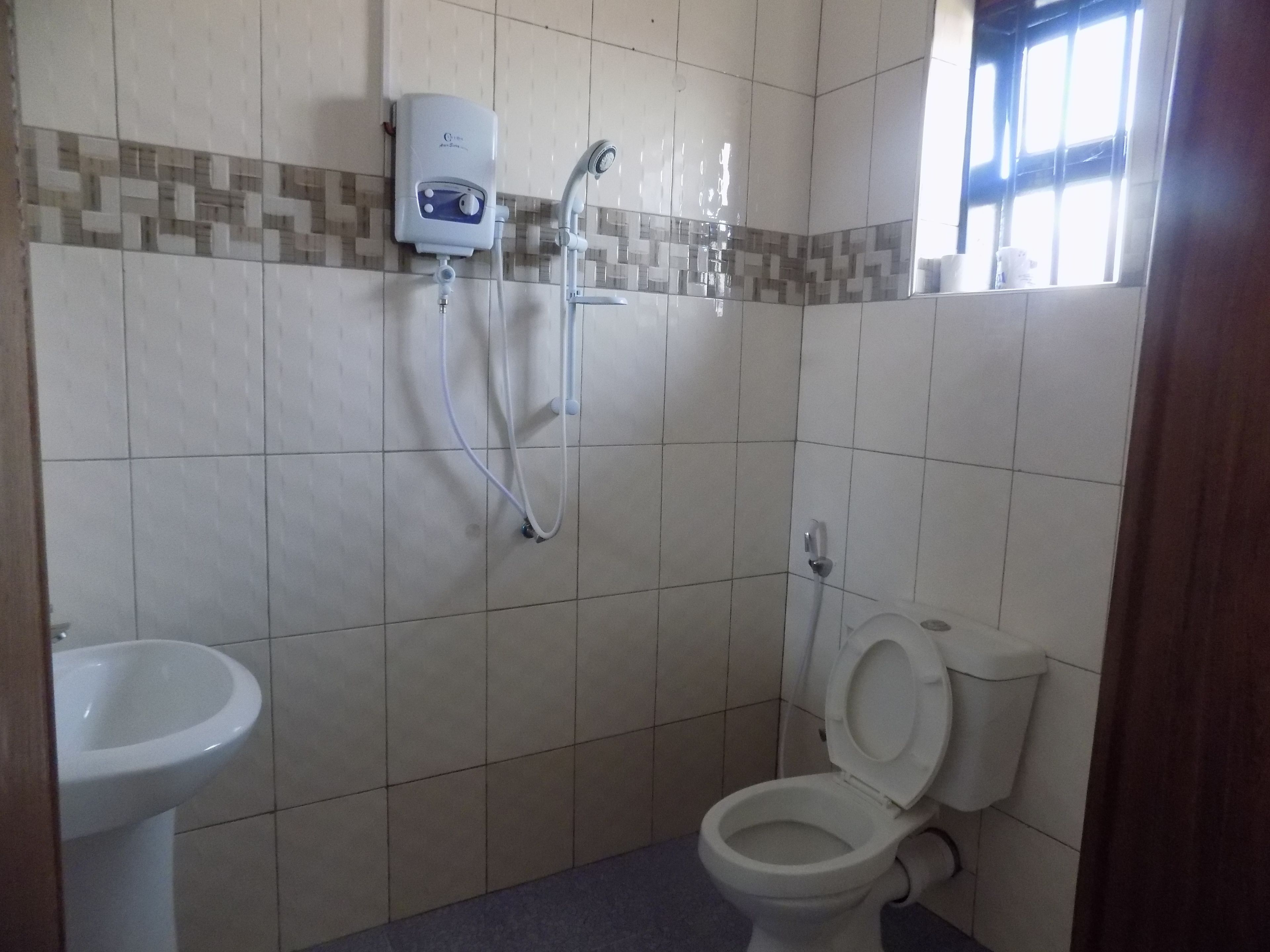 Une salle de bain équipée de toilettes, d’un bidet et d’une douchette à main.