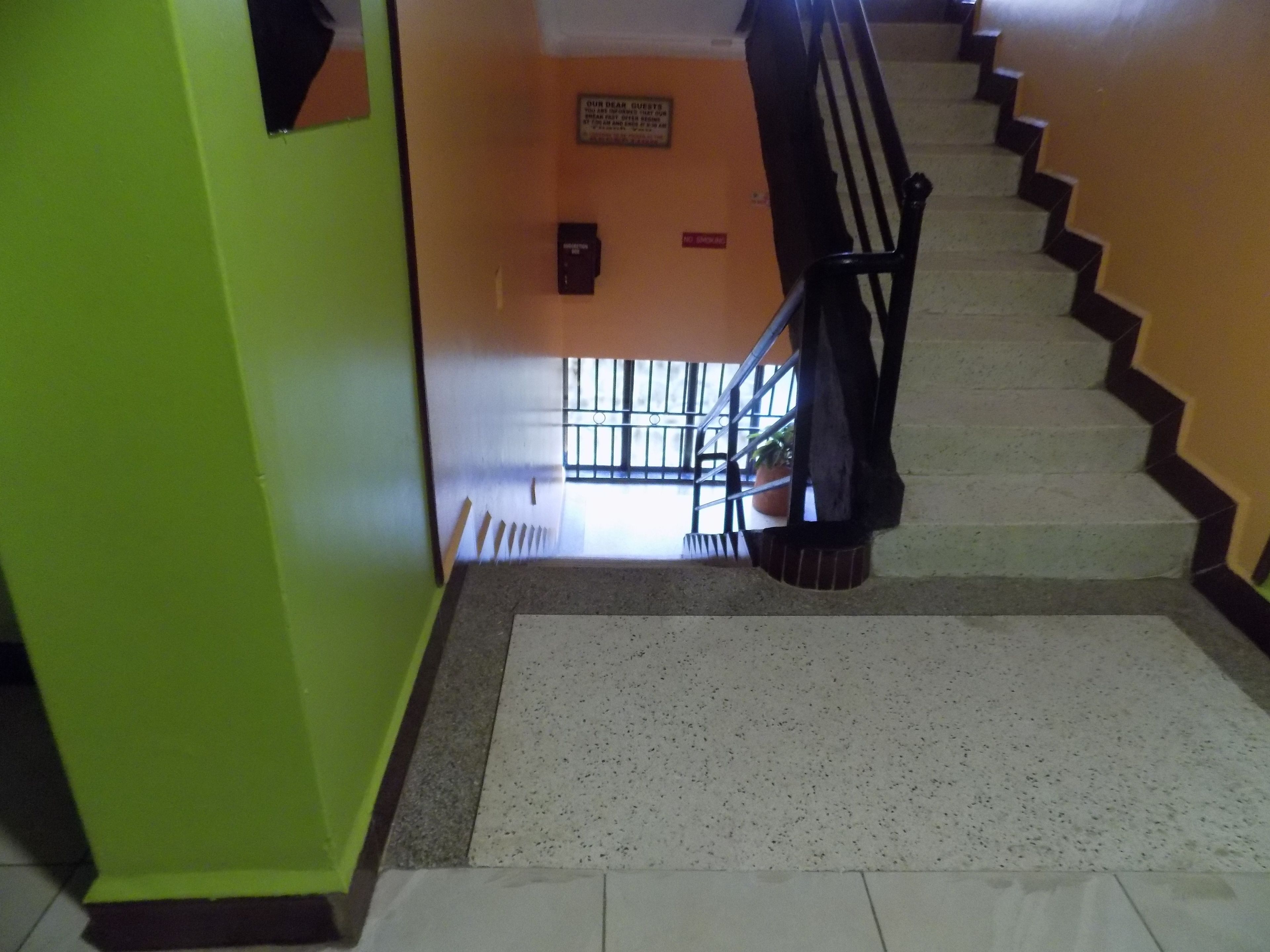 A staircase with a handrail, a sign on the wall, and a window with bars.