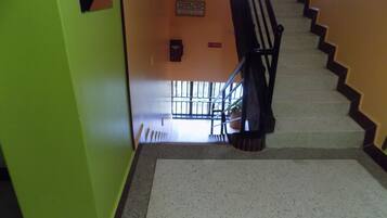 A staircase with a handrail, a sign on the wall, and a window with bars.