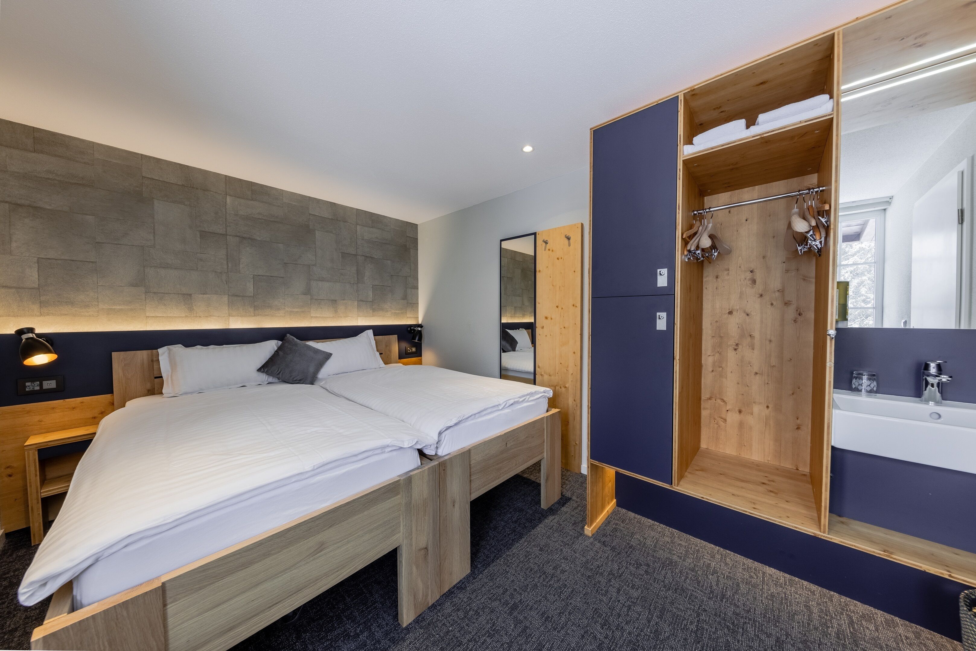 A modern bedroom with a large bed, wooden wardrobe, and a built-in shower.
