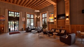 Un hall d’entrée spacieux avec des poutres en bois, de grandes fenêtres, un sapin de Noël et un téléviseur à écran plat.
