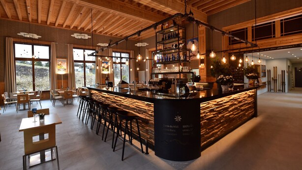 Un espace bar moderne avec un comptoir en pierre, des tabourets de bar et des luminaires suspendus.