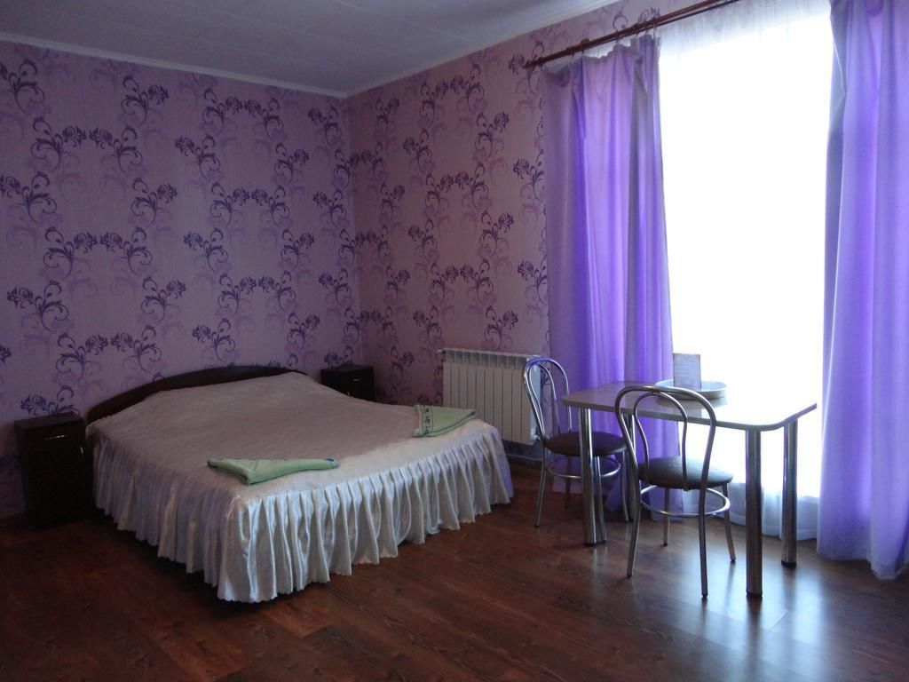 A bedroom with a bed, a table, two chairs, and a radiator.