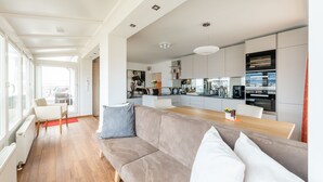 A modern living room with a sofa, a dining table, and a kitchen area with cabinets and appliances. - Skyflats Vienna Belle View (Vienna)