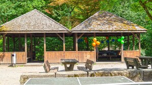 Two wooden gazebos with picnic tables and benches, surrounded by trees. - Sunny & Stylish 3 Bedroom Apartment, 20 min from city centre. 1st Floor. (Kreis 7)