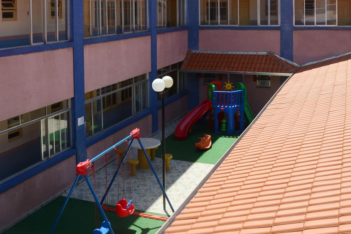 Un immeuble à plusieurs étages doté d’un espace de jeux pour enfants comprenant des balançoires, un toboggan et une structure d’escalade.