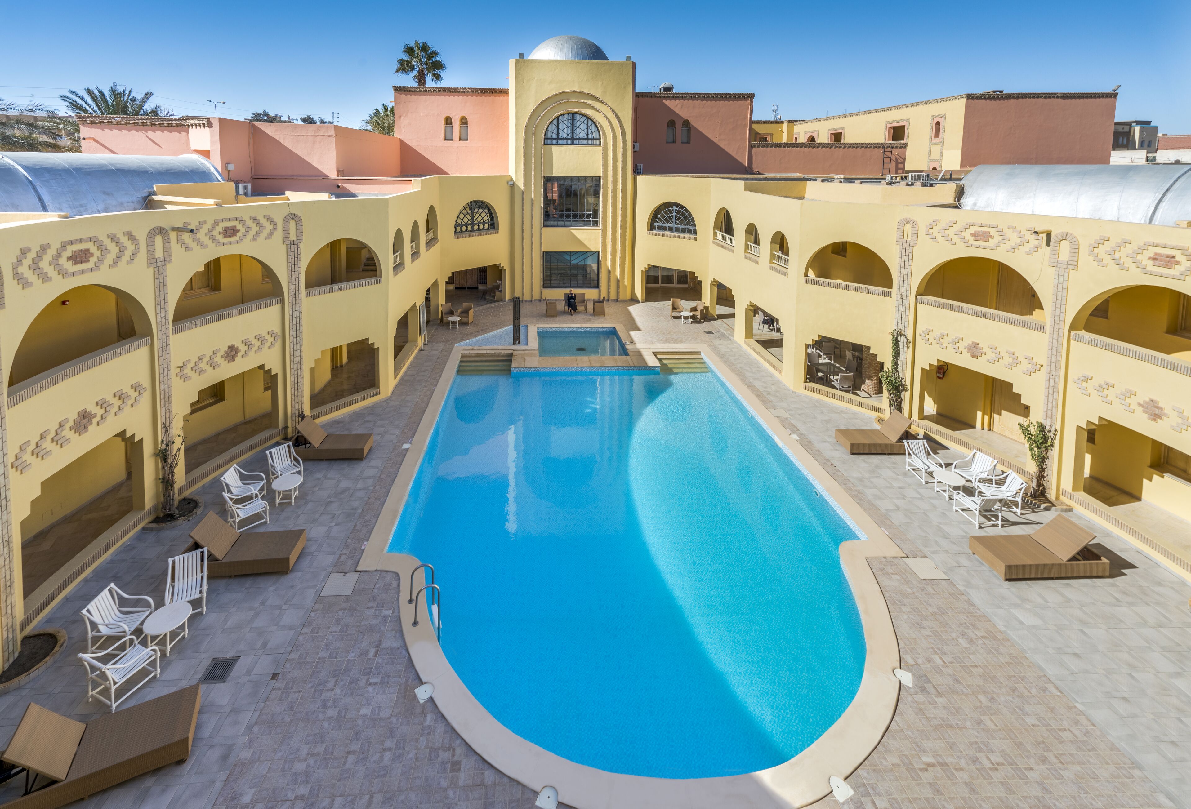 A pool area with a central pool, lounge chairs, and a covered seating area.