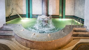Un jacuzzi con una fuente de agua, rodeado de escalones y paredes de azulejos.