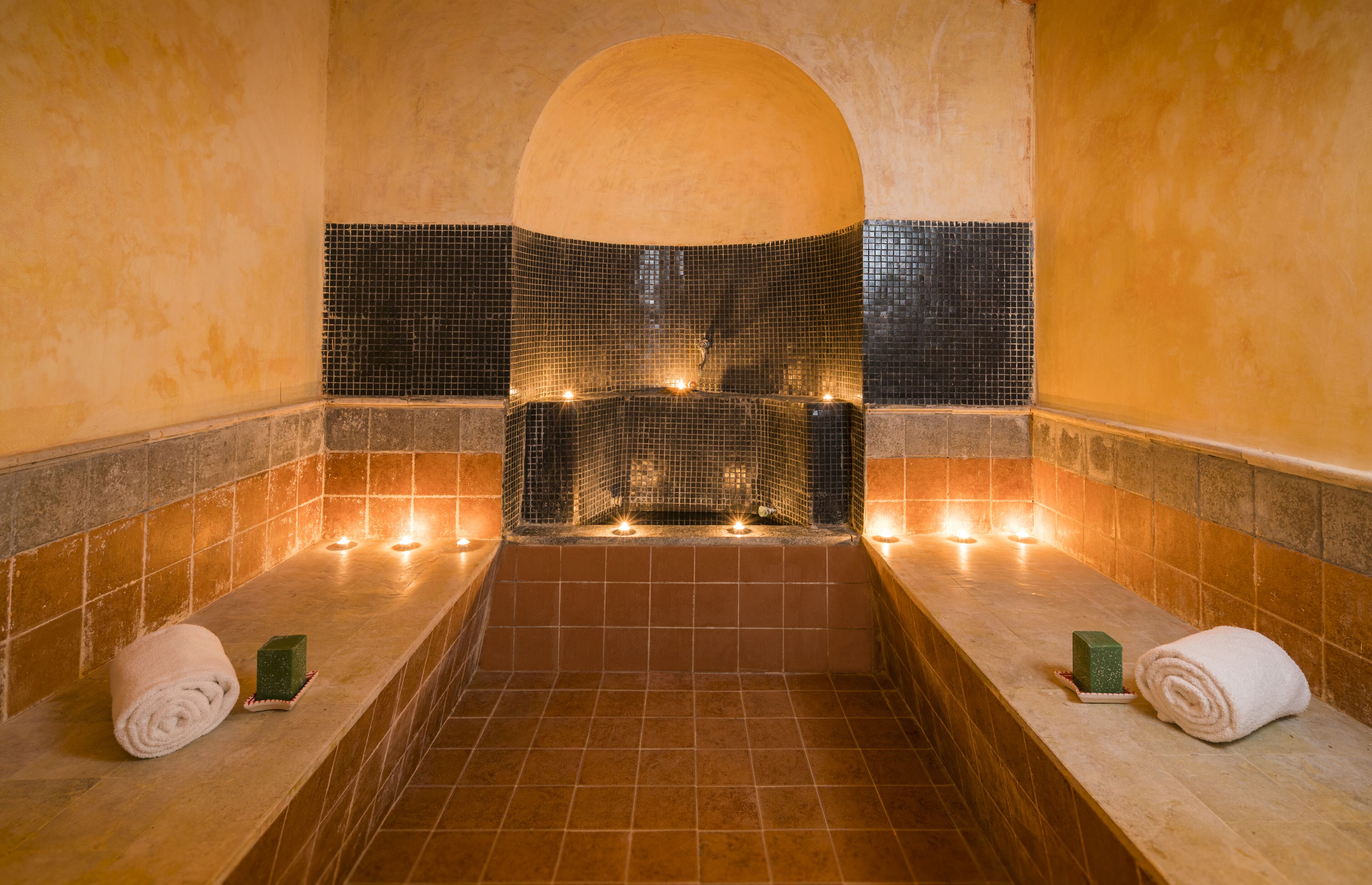 A spa area with a large bathtub, tiled walls, and candles.