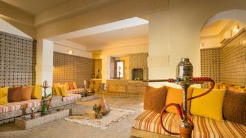 A spacious living area with a sofa set, a coffee table, and a hookah.
