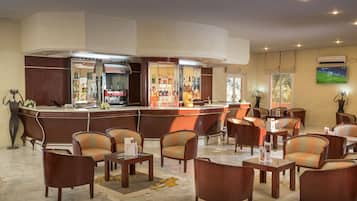 Eine Bar mit einer Theke, Getränkeauswahl in Regalen und einem an der Wand befestigten Fernseher.
