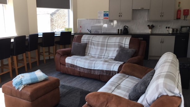 Un salon comprenant un canapé, un pouf et un coin repas avec des chaises et une table.