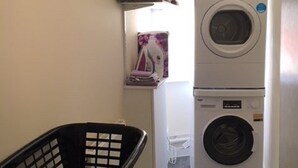 Un espace dédié à la lessive, avec des piles de serviettes, un lave-linge et un panier à linge.