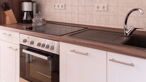 Una cucina moderna con mobili bianchi, un forno in acciaio inossidabile, una macchina da caffè e un lavello.