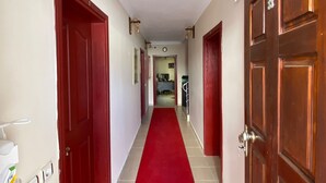 A hallway with red carpet, wooden doors, and light fixtures. - Sualti Otel (Ayvalik)