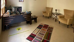 A living room with a desk, two chairs, a patterned rug, and a ceiling fan. - Sualti Otel (Ayvalik)