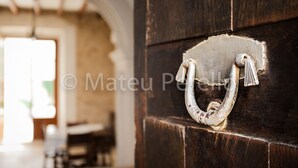 Una puerta de madera rústica con un tirador de metal en forma de anillo.