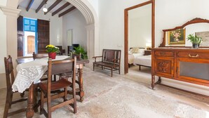 Un comedor con una mesa de madera, sillas y un banco. Hay un espejo grande en la pared y un mueble con un espejo encima.