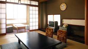 Una habitación tradicional japonesa con suelo de tatami, una mesa baja y puertas correderas shoji.