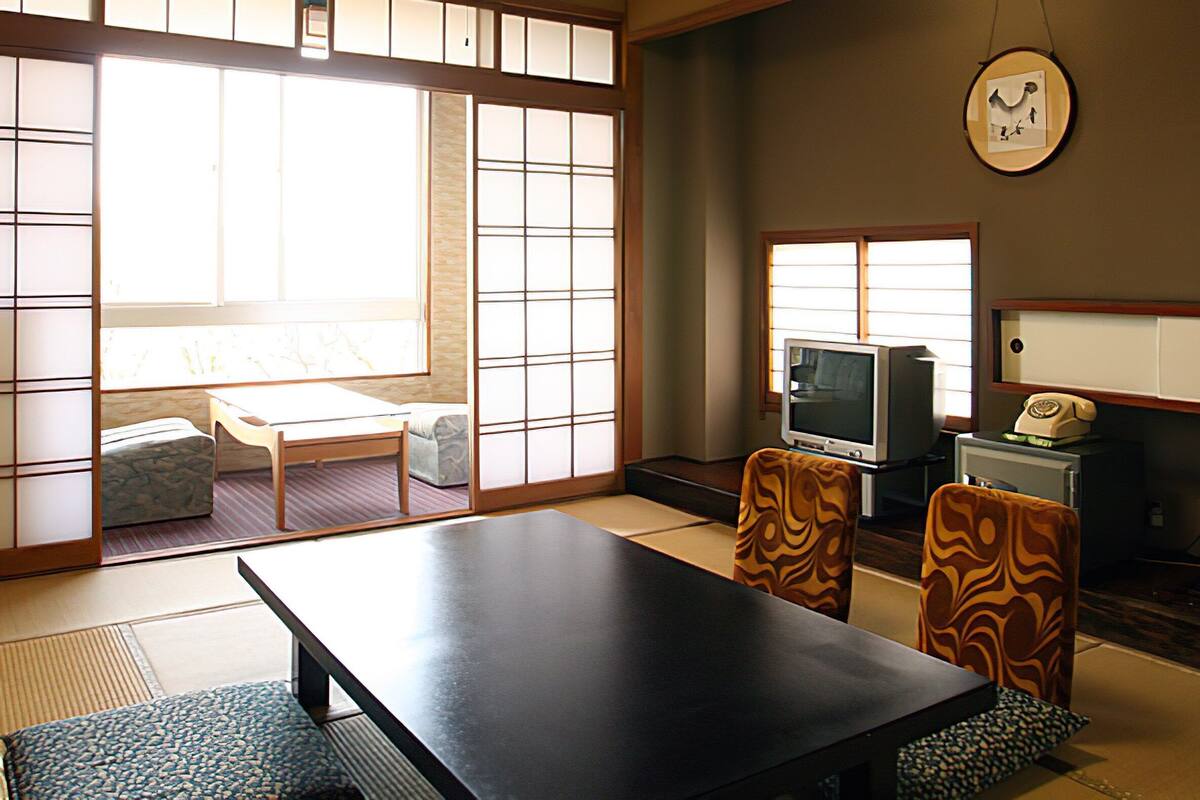 Um quarto japonês tradicional com tatames, uma mesa baixa e biombos shoji.