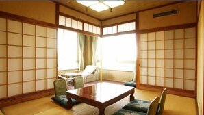 Una habitación japonesa tradicional con suelo de tatami, una mesa de madera baja y puertas correderas shoji.