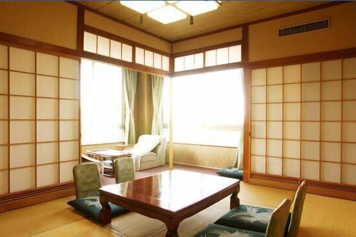 Um quarto japonês tradicional com tatames, uma mesa de madeira baixa e biombos shoji.