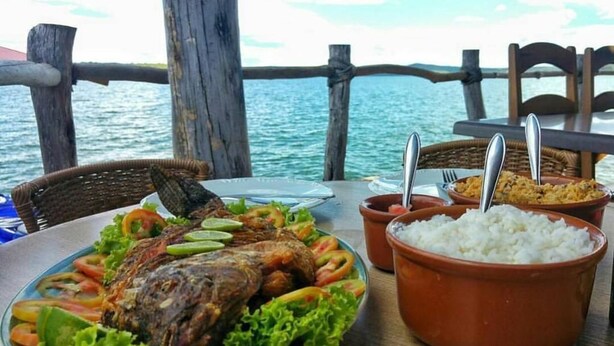 Ein Teller mit Meeresfrüchten, Reis und Gemüse an einem Tisch am Wasser.