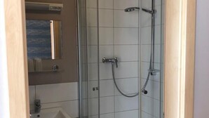 A modern bathroom with a glass-enclosed shower, a sink, and a mirror. - greenpartment Boardinghouse Hotel Ingolstadt Friedrichshofen (Ingolstadt)