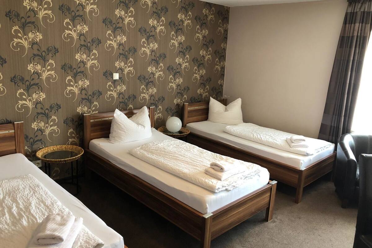 Ein Hotelzimmer mit zwei Einzelbetten, einem runden Tisch und einem Stuhl.