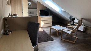A modern loft bedroom with a sloped ceiling, a desk, a chair, a TV, and a skylight. - greenpartment Boardinghouse Hotel Ingolstadt Friedrichshofen (Ingolstadt)