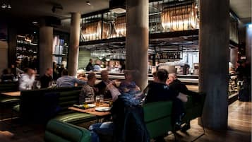 Eine moderne Bar mit hohen Decken, freiliegenden Balken und einer zentralen Bar.