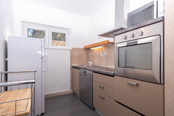 A compact kitchen with a built-in oven, a dishwasher, and a window above the sink.