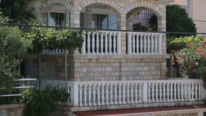 A two-story building with a white balcony, a garage, and a stone facade. - Villa Mara (Slivno)