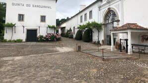 Une cour pavée de pierres, avec un bâtiment blanc portant l’inscription « QUINTA DO SANGUINHAL ».