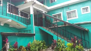 Un edificio de varios pisos con escaleras, balcones y fachada verde.
