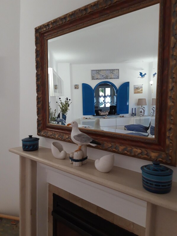 A room with a fireplace, a mirror, and decorative items including a seagull sculpture and a blue pot. - Sun terrace with beautiful sea views, 4 beautiful beaches, quiet location (Ferragudo)