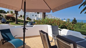 A terrace with outdoor seating, a view of the sea, and a parked car. - Sun terrace with beautiful sea views, 4 beautiful beaches, quiet location (Ferragudo)