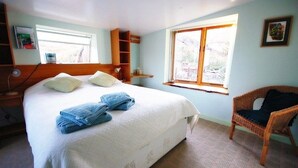 Ein Schlafzimmer mit Bett, Stuhl, Fenster und Regal.