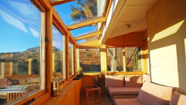 Ein gemütliches Zimmer mit Holzvertäfelung, großen Fenstern und einem Sofa.