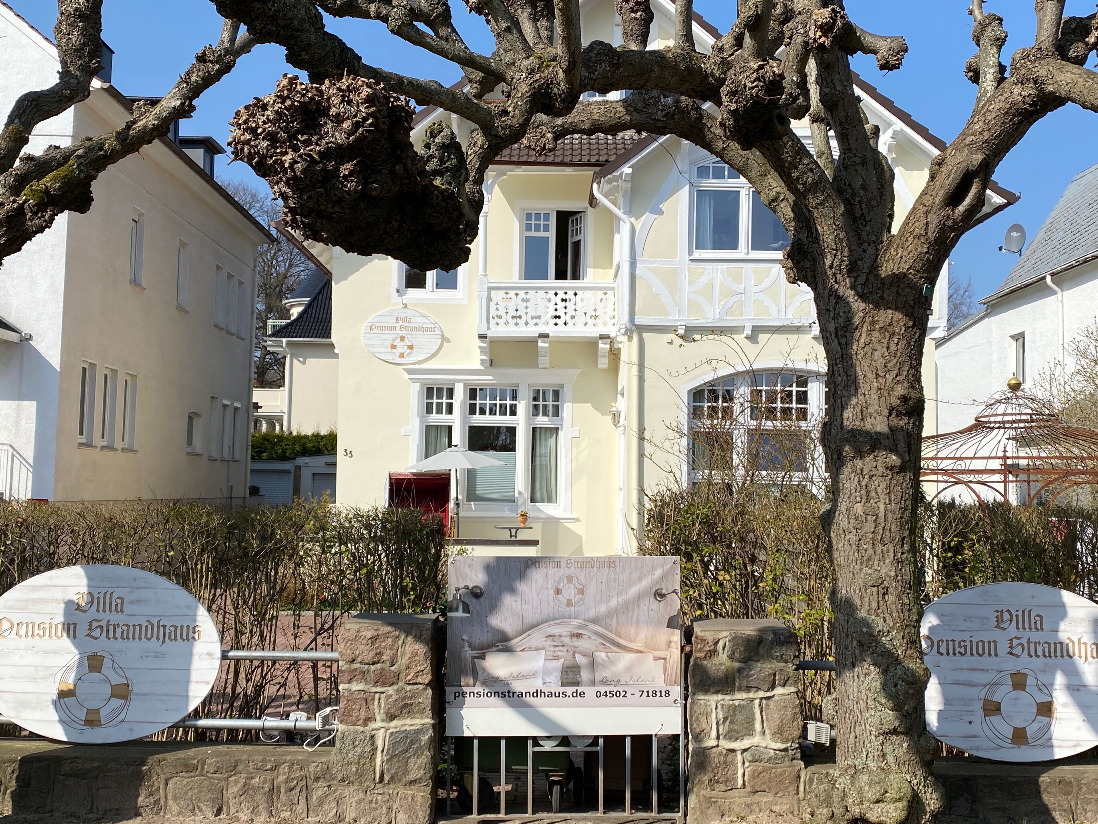 Villa Pension Strandhaus con entrada de pared de piedra, un balcón y vista despejada del edificio contiguo.