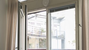 A room with a sliding glass door leading to a balcony, a grey sofa, and a small table. - 2ndhomes Kluuvi Studios (Helsinki)